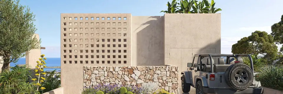 Acceso a la villa con celosía de hormigón y muro de piedra seca